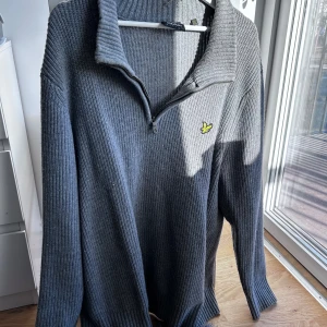 Grå stickad Half Zip från Lyle & Scott - Säljer en stilren grå stickad tröja från Lyle & Scott med dragkedja vid halsen och deras ikoniska logga på bröstet. Perfekt för kyligare dagar och ger en klassisk look. Passar bra till både jeans och chinos. Hör av er vid intresse/frågor!