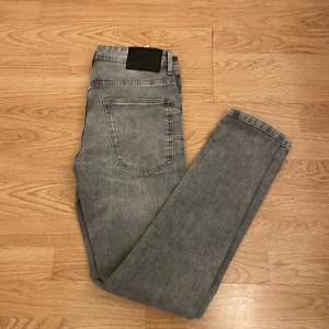 Grå jeans från FSBN - Snygga grå jeans från FSBN med en klassisk femficksdesign. De har en knappgylf och är tillverkade i ett slitstarkt denimtyg. Perfekta för en stilren look. Skriv om ni har funderingar och priset är inte hugget i sten!