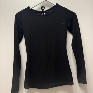 Svart långärmad topp med öppen rygg - Snygg svart långärmad topp med en stilren design och öppen rygg. Perfekt för en trendig look med knytband i nacken 💓