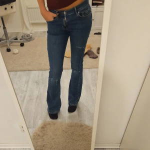 Blåa jeans med hål - Säljer dessa jätte fina jeans från bikbok,ända defekten är sista bilden då jag har satt en lapp för hålet,lappen går att dra bort💕 Innerbenslängden är 76 och midjemått är 36,men dom ät väldigt stretchiga 😄