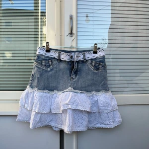 Jeanskjol med volang - Supersöt denimkjol med en vit volang och spetsdetaljer runt midjan!😇💓 Ingen storlekslapp inuti men sitter som en XS/S💓 I bra skick! Jag hittar inga defekter💓 Rakt över midjan, 35cm Längd, 39,5cm