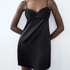 Svart zara klänning - Elegant svart klänning med smala axelband och spetsdetaljer vid bysten. Tillverkad i ett glansigt material som ger en lyxig känsla. Perfekt för en stilren look. Helt ny med prislapp kvar, helt slutsåld💘💘💘Föreslå pris vill få den såld!!