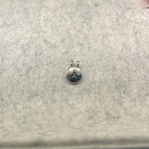 Silverberlock med bokstaven A - Söt liten rund silverberlock med bokstaven A ingraverad. Perfekt att fästa på ett armband eller halsband för en personlig touch.   SKRIV OM PRISFÖRSLAG 