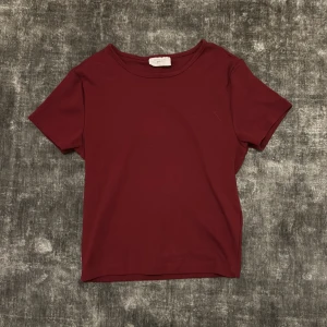 Vinröd t-shirt från Gina Tricot - en vinröd magtröja från Gina Tricot. Passar till många olika outfits och tillfällen. (Aldrig använd)