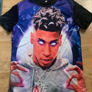 Svart t-shirt med grafiskt tryck - Cool t-shirt med ett färgstarkt grafiskt tryck av en tecknad figur med lysande ögon. T-shirten har korta ärmar och en svart bas som gör att trycket verkligen poppar. Perfekt för dig som vill sticka ut!