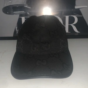 Svart keps med monogrammönster - Snygg svart keps med diskret monogrammönster. Perfekt för en stilren look. Justerbar passform baktill för optimal komfort.