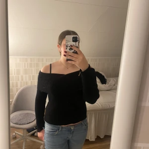 Svart offshoulder tröja från H&M - Säljer en stilren svart offshoulder tröja från H&M. Tröjan har en ribbad struktur och långa ärmar, perfekt för en trendig look. Passar bra till både jeans och kjol.