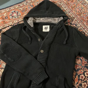 Svart stickad hoodie! - Säljer otroligt snygg, unik och skön hoodie från Tom tailor. Den har väldigt snygga detaljer som camo mönstret i luvan! Denna är size M men tycker den sitter som en S.