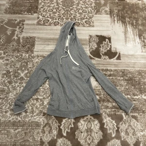 Grå huvtröja från Boss - Säljer en stilren grå huvtröja från Boss med dragkedja och justerbar huva. Perfekt för en avslappnad look. Tröjan har långa ärmar och en liten logga på bröstet. Passar bra till både jeans och joggers.