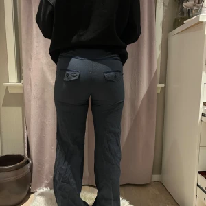 Mörkblå byxor med knappar - Snygga mörkblå byxor med knappar bak och en diskret randig design. Perfekta för en stilren look. De har en rak passform och är tillverkade i ett bekvämt material.