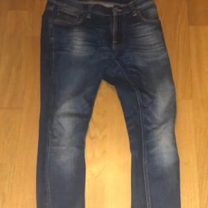 Mörkblå jeans från Nudie Jeans - Snygga mörkblå jeans från Nudie Jeans med en klassisk femficksdesign. De har en lätt slitning på låren och knäna för en trendig look. De är slim fit. 30w och 30L