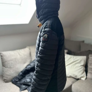 Grå dunjacka från Parajumpers - Säljer en snygg grå dunjacka från Parajumpers med huva och dragkedja. Jackan har en quiltad design och en cool patch på ärmen. Perfekt för kyliga dagar. Ser lite skrynklig ut på bilderna då den legat nerpackad ett tag.. priset är diskuterbart🥰