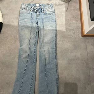 Ljusblå jeans från 157 - Snygga ljusblå jeans från 157 med hög midja och bootcut-stil. De har en klassisk femficksdesign och dubbla knappar i midjan. Perfekta för en avslappnad look.