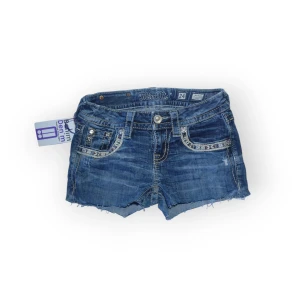 Blå jeansshorts från Miss Me - Jeansshorts från Miss Me med slitna kanter och broderade detaljer på bakfickorna. Midja:34, längd:22 💗 Finns slitningar, knappen har ersatts och bokstaven på baksidan har fallit av. Säljer billigt av denna anledning 