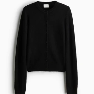 Svart kofta med knappar - Snygg och stilren svart kofta med knappar framtill. Perfekt för lager-på-lager och passar till många olika outfits. Långärmad design som håller dig varm under kyligare dagar.