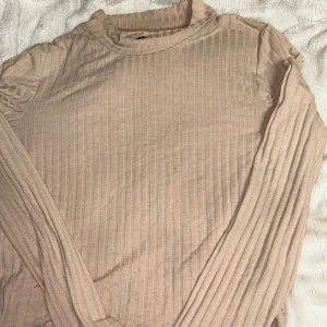 Beige långärmad tröja - Säljer en stilren beige långärmad tröja. Perfekt för en enkel och snygg look. Tröjan har en tight passform som framhäver figuren. Passar bra till både jeans och kjol. Tröjan är från stay, köpt i Paris och de står L på den men den sitter som S eller M 