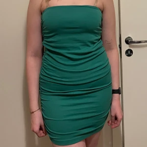 Grön axelbandslös klänning - Snygg grön axelbandslös klänning från Zara  med rynkade detaljer på sidorna. Perfekt för en kväll ute eller en speciell tillställning. Klänningen har en tight passform som framhäver figuren.