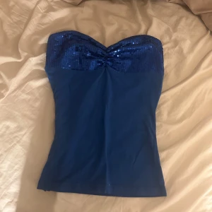 Mörkblå tubtopp med paljetter - Snygg mörkblå tubtopp med glittrande paljetter upptill. Perfekt för en kväll ute eller festliga tillfällen. Toppen har en elegant och stilren design. Den är figursydd.☺️