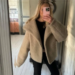 Beige teddyjacka - Säljer en mysig beige teddyjacka med oversized passform. Jackan har en stor krage och knappar framtill. Perfekt för kyliga dagar när du vill vara både varm och stilren.