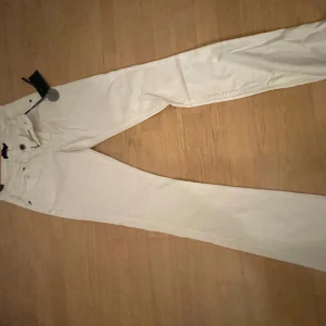 Vita bootcut jeans från Seven - Snygga vita bootcut jeans från Seven med medelhög midja. Perfekta för en stilren look. De har en klassisk design med fem fickor och knappgylf.
