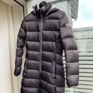 Fin och varm dunjacka från Colmar i storlek S/36-38. Utmärkt skick, ett litet snitt på insidan av huvan bild 5, påverkar ingenting. 1-2cm  Bälte ingår. Färgen är mörkbrun, nästan svart. Nypris ca 6000  