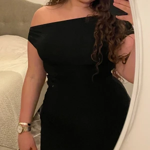 Svart offshoulder klänning - Elegant svart offshoulder klänning med en tight passform. Perfekt för en stilren och sofistikerad look. Klänningen har en klassisk design som framhäver axlarna.
