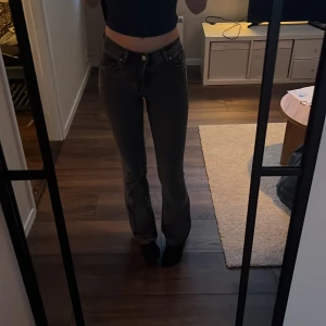 Svarta/gråa bootcut jeans - Snygga svarta/gråa bootcut jeans med en klassisk femficksdesign. De har en dragkedja och knapp framtill. Köpt från gina tricot. 