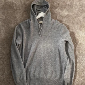 Grå hoodie från Sayless - Mysig grå hoodie från Sayless i kashmir. Perfekt för kyliga dagar med sin mjuka och bekväma passform. Den har en klassisk design med ribbade muddar och en praktisk huva.