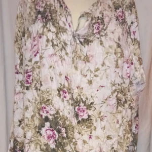 Blommig blusaktig från Cellbes - Charmig blommig blusaktig från Cellbes i mjuka toner av rosa och grönt. Blusen har en romantisk känsla med sitt vackra blommönster och är perfekt för vår och sommar. Den har en bekväm passform och är tillverkad i ett lätt material.