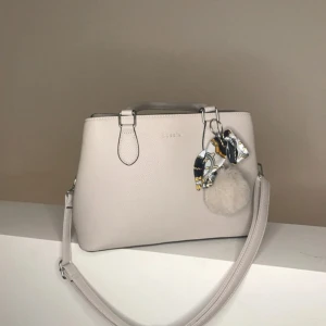 Puccini handväska  - Super fin Puccini handväska som jag tyvärr inte har fått användning av. Köpte den för några månader sedan så den är i super bra skick, inga skador eller liknande. Bra förvaring med flera fickor och en gullig dekor som kommer med ( se på första bilden). Köpte den för 799 på Lundbergs!! 