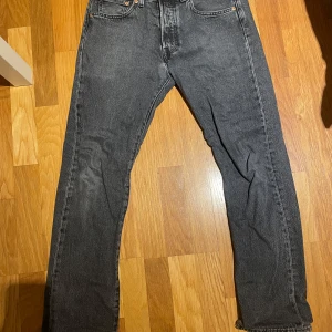 Grå Levis 501 jeans - Säljer ett par klassiska grå Levis 501 jeans. De har en straight passform och är tillverkade i slitstarkt denim. Perfekta för en avslappnad stil.