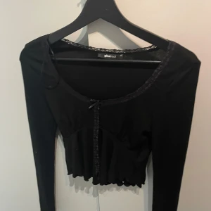 Svart långärmad topp från Gina Tricot - Snygg svart långärmad topp från Gina Tricot med spetsdetaljer. Perfekt för en stilren look.