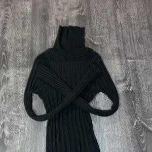 Svart ribbad polotröja från ASOS DESIGN - Säljer en stilren svart ribbad polotröja från ASOS DESIGN. Tröjan har en hög krage och långa ärmar, perfekt för kyligare dagar. Den är både bekväm och trendig, ett måste i garderoben!