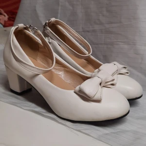 Vita Klackskor med rosetter - Super fina klackskor med rosetter! Små tecken på användning vilket syns på bilderna. ❗️Det står att de är storlek 38 men skulle säga att de är 37 (har själv vanligtvis 38 och de var för små för mig).❗️ Vet inte vilket märke de är då det inte står på dem och jag har köpt dem från sellpy.  Skriv gärna om du undrar något!🥰