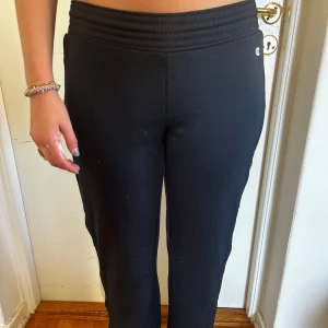 Svarta mjukisbyxor från Champion - Säljer ett par svarta mjukisbyxor från Champion. De är superbekväma med resor midja och knappar längs sidorna för en cool look. Perfekta för en avslappnad dag.