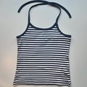 Randig halterneck-topp - Halterneck-topp i vitt och mörkblått (nästan svart) som man knyter i nacken. Har barnstorlek 134/140 men den passar mig och jag skulle jämföra den med storlek XS. På ena bandet har sömmen släppt någon cm (se bild) men det går lätt att sy igen!