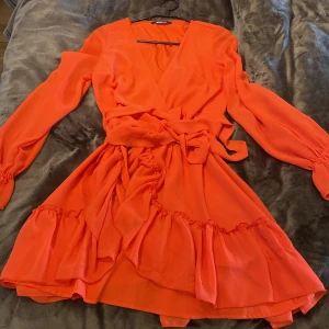 Röd/orange klänning - Omlottklänning superfin, använd fåtal gånger! Storlek 34 men passar mig som har 36 också. Säljes för 50kr