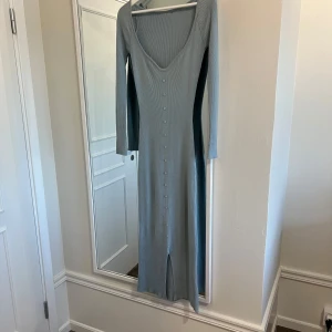 Ljusblå ribbad långklänning - Ljusblå långklänning med ribbad struktur och v-ringning. Klänningen har långa ärmar och är i storlek Xs i ett stretchigt material