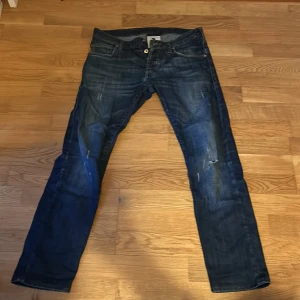 Mörkblå jeans från Emporio Armani - Snygga mörkblå jeans från Emporio Armani med klassisk femficksdesign och knappgylf. Jeansen har en diskret tvättad look och en broderad logga på bakfickan. Perfekta för en stilren vardagslook.