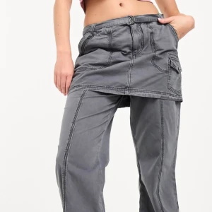 Grå cargopants med kjoldetalj - Unika grå cargopants med inbyggd kjol! Byxorna har en loose passform och flera praktiska fickor, inklusive en sidoficka med knapp. Använd fåtal gånger:)