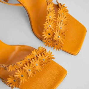 Poppy sunflower gloss grained leather BY FAR - Snygga gula sandaler/klackar från By Far med blommiga detaljer och klack. Perfekta för att lysa upp din outfit med en somrig touch. Skorna har en fyrkantig tå och justerbara remmar för bästa passform. Skorna är enbart provade och hållits förvarad i boxen. Nypris: 5350kr. Slutsålda på byfar, tillverkas inte längre. 