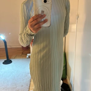 Grön ribbad klänning från Shein - Snygg grön ribbad klänning från Shein med långärmad design. Perfekt för en stilren look med sin enkla men eleganta stil. Klänningen är i en mjuk och bekväm passform.