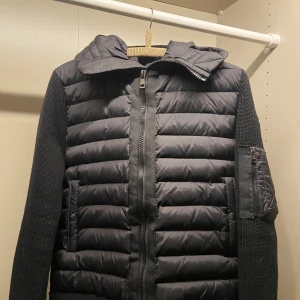 Moncler Cardigan, svart - Säljer min killes Mocler Cardigan då den inte kommer till användning mer.  Mycket bra skick och inga defekter. Den fungerar även som M. Han är 193cm. Pris kan diskuteras och fler bilder finns om ni vill ha!☺️