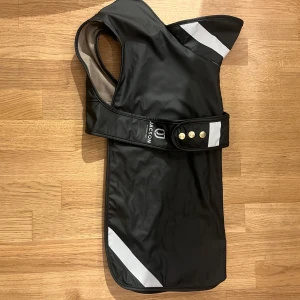 Svart regntäcke/hundjacka från Jacson - Regntäcke/hundjacka från Jacson med reflex & fodrad. Använd 2 ggr- som ny.