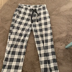 Rutiga pyjamasbyxor från Kappahl - Säljer ett par bekväma och stiliga rutiga byxor från Kappahl i storlek XS. Byxorna har ett svartvitt mönster och är utrustade med en praktisk snörning i midjan för bästa passform. 70kr + frakt dem är mindre i storleken så passar för strlk 146/150