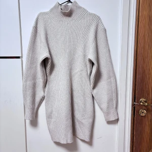 Beige ribbad polotröja - Säljer en stilren beige poloklänning med ribbad struktur. Klänningen har långa ärmar och en hög krage som ger extra värme. Perfekt för kyliga dagar! Använt endast två gånger pga känner mig obekvämt av polon.