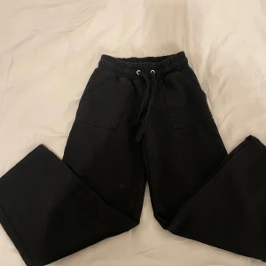 Svarta mjukisbyxor - Säljer ett par svarta mjukisbyxor med elastisk midja och snörning. Byxorna har fickor både fram och bak, vilket gör dem praktiska och bekväma. Perfekta för en avslappnad stil.