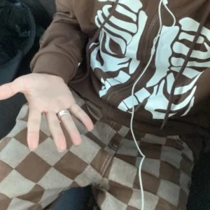 Brun y2k hoodie med skelettmönsterr - Cool brun hoodie med ett iögonfallande vitt skelettmönster på framsidan och ärmarna. Den har dragkedja och långa ärmar, perfekt för en unik stil. Säljs pga ändrat stil. 