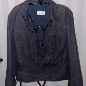 Mörkblå jeansjacka från Lecomte ny - Snygg mörkblå jeansjacka från Lecomte med klassisk design. Jackan har knappar framtill och två bröstfickor med lock. Perfekt för en casual look.