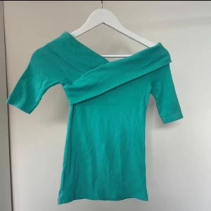 Turkos offshoulder topp från Gina Tricot - Snygg turkos offshoulder topp från Gina Tricot i ribbat material. Perfekt för en stilren look med en unik design . Passar bra till både jeans och kjol. Använd 2 gånger! 